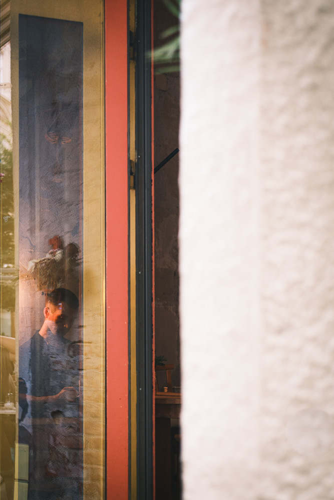 Blick durch das reflektierende Fenster eines roten Rahmens auf eine Person, die nach unten sieht.